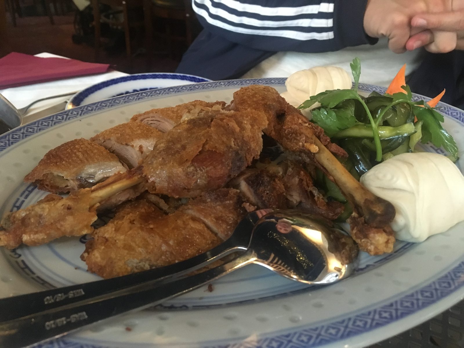 Xiang Su Ente. In Kaoliang eingelegte Ente, knusprig gebraten, gewürzt mit Anis und Pfeffer, mit einer pikanten Knoblauchsauce, dazu gedämpfte Hefeteig-Lotusblätter