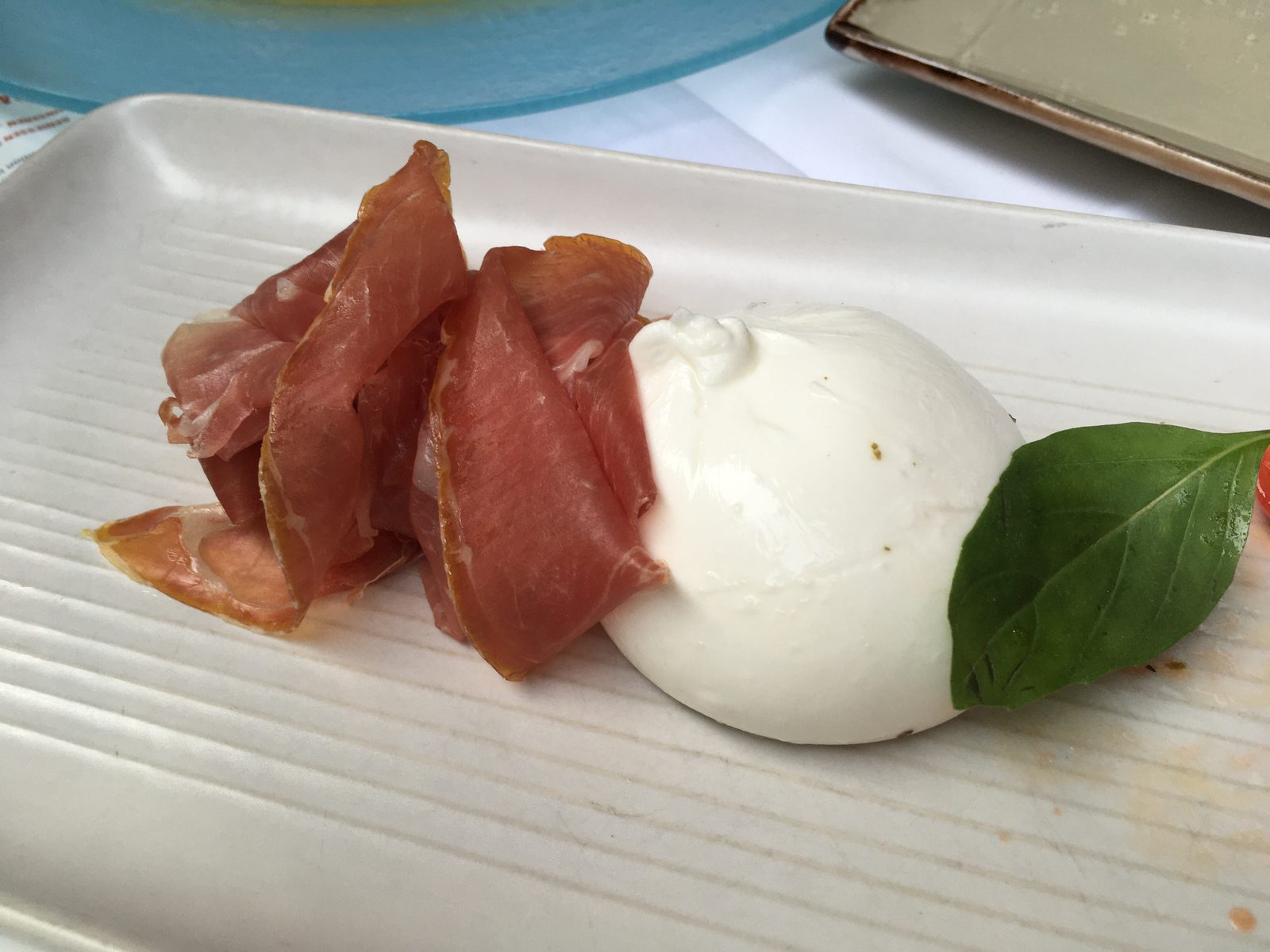 BURRATINA PUGLIESE CON DATTERINO, BASILICO E SANT ILARIO
(Frischer Burrata mit Datteltomaten, Basilikum und Sant  Ilario-Schinken)